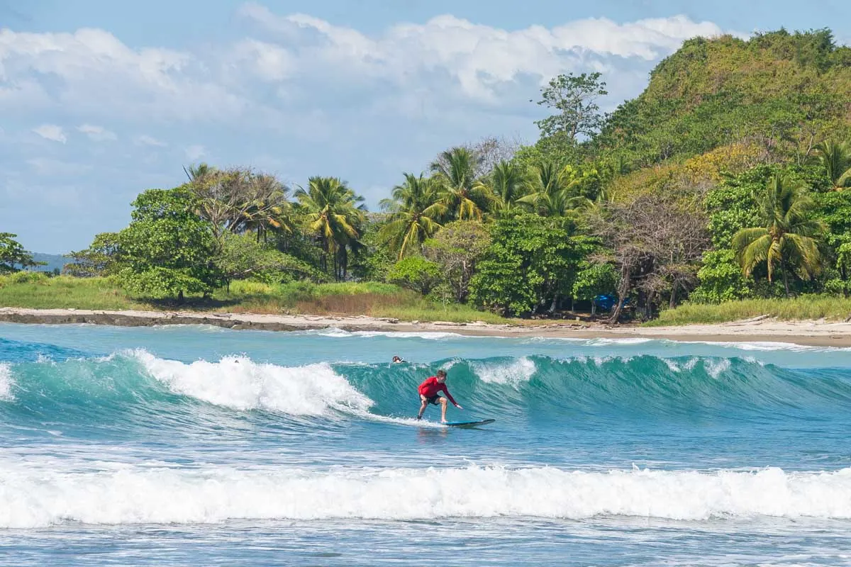 Beginner surfer catching a wave at Playa Hermosa, one of the best Santa Teresa surf spots beginner options